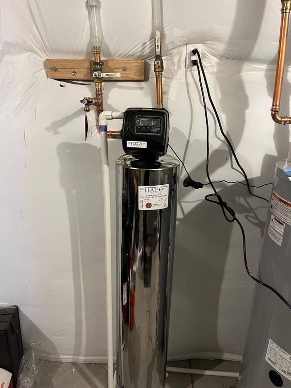 Stainless steel HALO whole-home water treatment tank with its control head, connected by copper bypass piping.